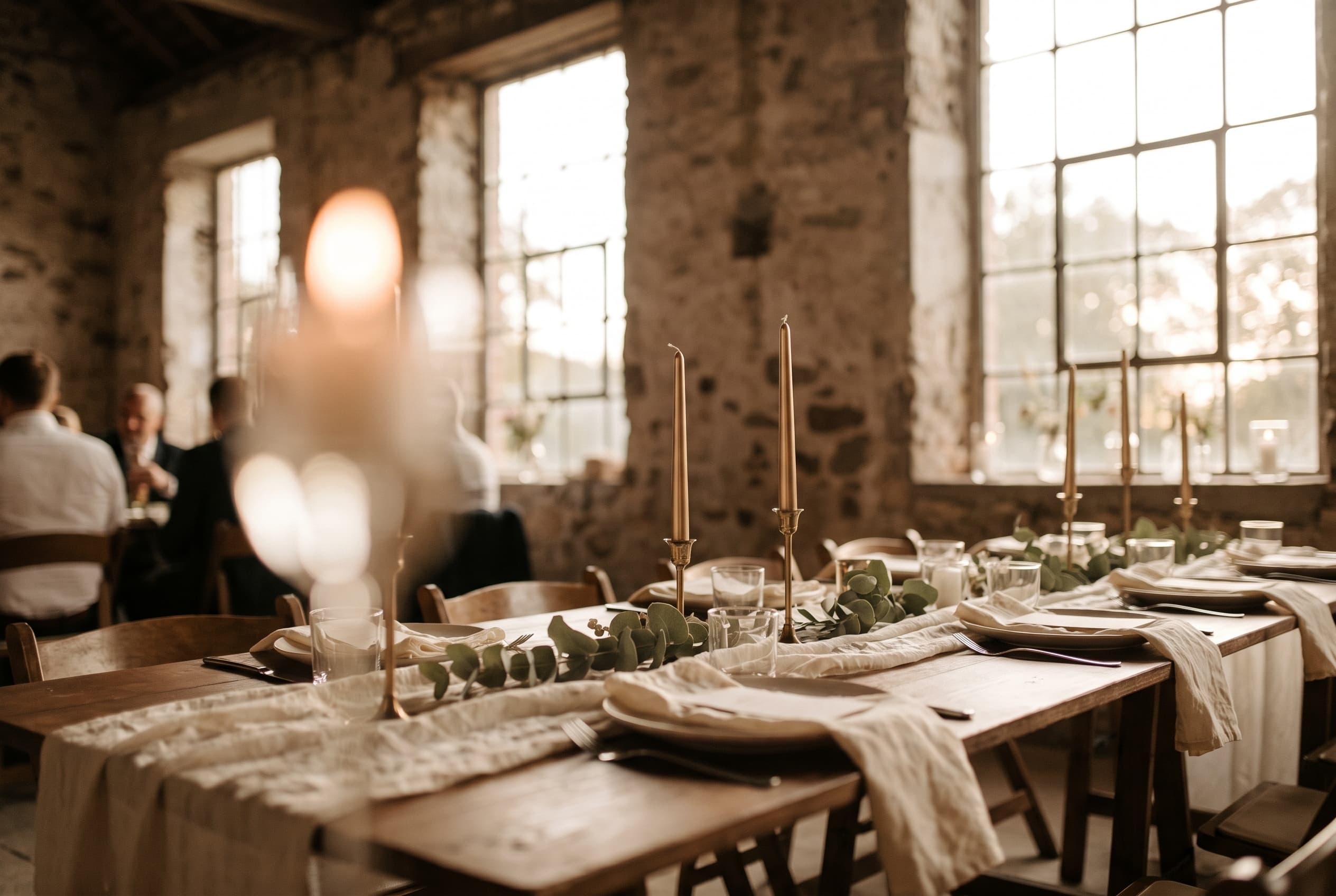 Table de réception de mariage en petit comité dressée avec élégance pour une dizaine de convives, bougies et eucalyptus, lumière dorée