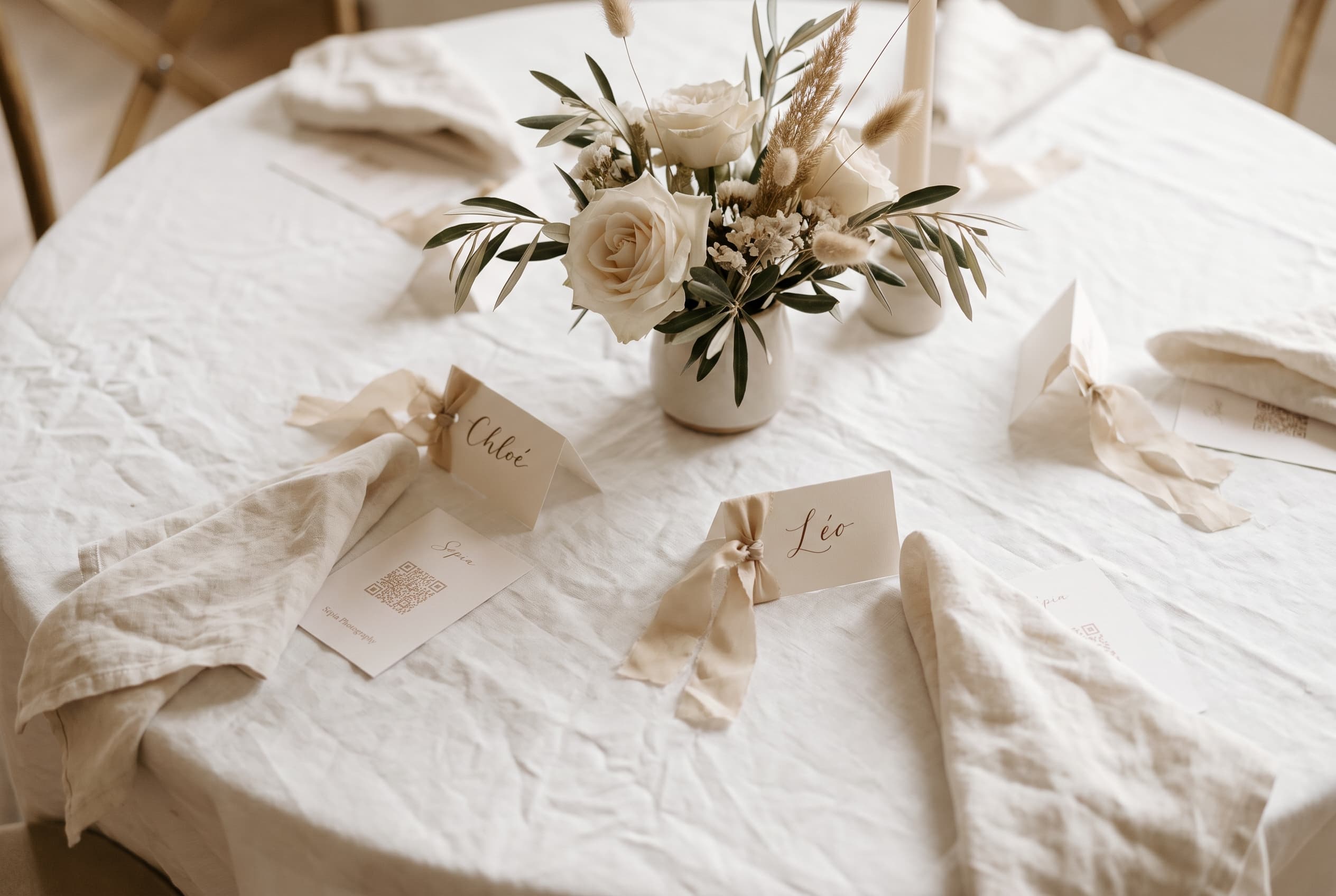 Vue du dessus d'une table de réception de mariage dressée avec nappe blanche et marque-places calligraphiés