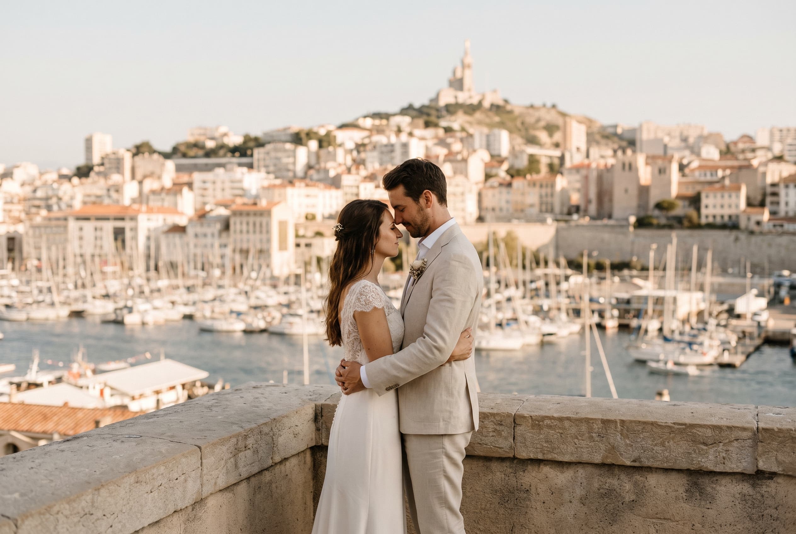 Couple de mariés sur une terrasse au-dessus du Vieux-Port de Marseille, Notre-Dame de la Garde en arrière-plan — galerie photo mariage à Marseille